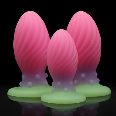 Pink liquid silicone anal plug set with luminous green suction cup base in three sizes S M L for adults
