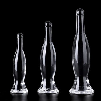 Three clear transparent bottle-shaped anal dildo plugs standing upright on black background